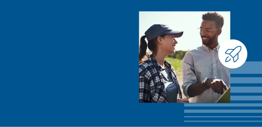 Eine Frau und ein Mann sprechen miteinander. Sie stehen draußen auf dem Feld. Vor blauem Hintergrund